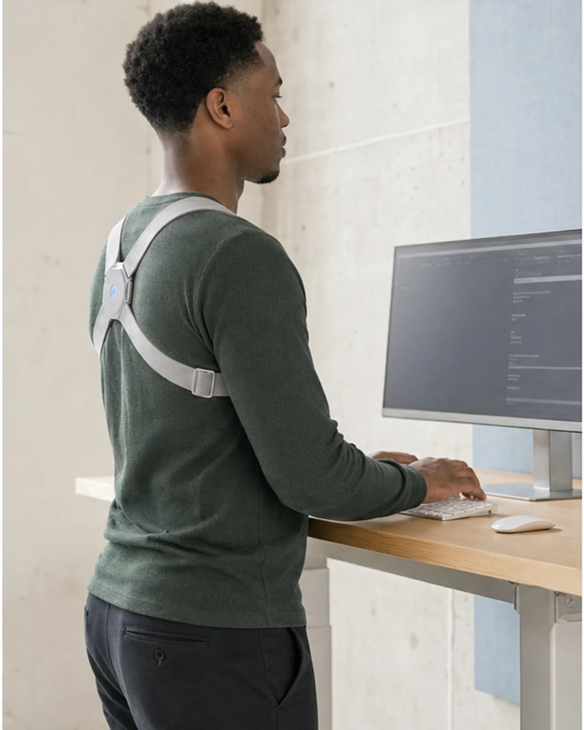 The same man working naturally at a standing desk while wearing AlignNova